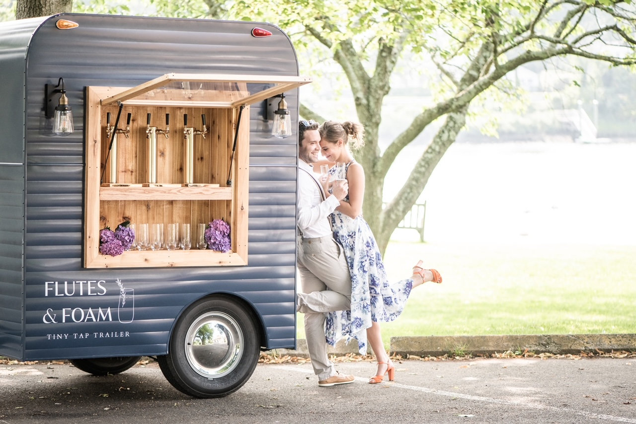 A couple beside the Flutes & Foam mobile tap trailer